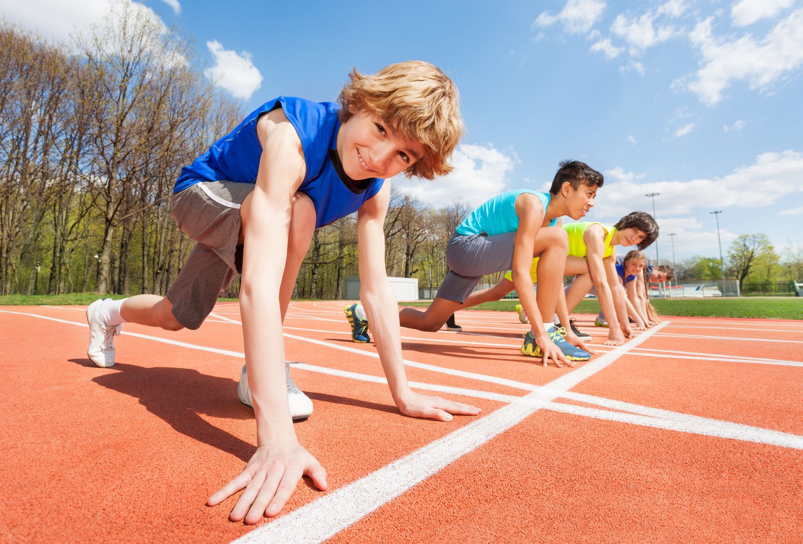 60507489 - teenage athletes preparing to start running on the track on the stadium, side view