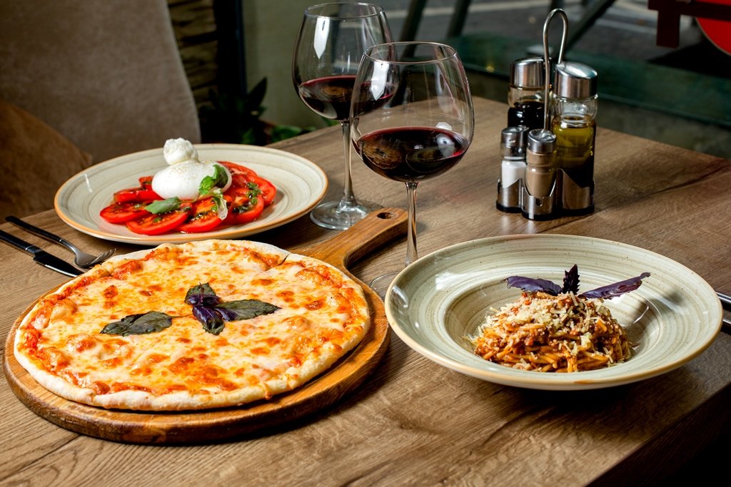 dinner set with margherita pizza salad pasta and wine